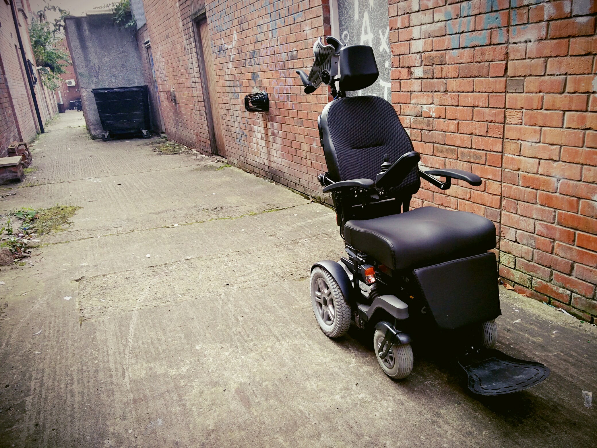 An electric wheelchair parked in a back alleyway in Belfast